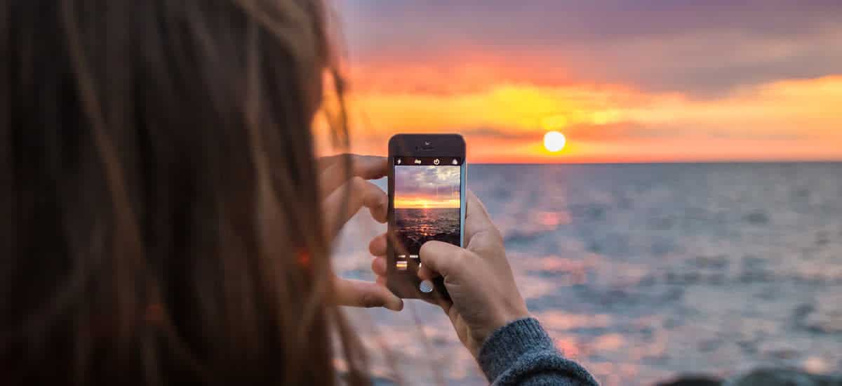 mujer-fotografiando-la-puesta-de-sol-con-un-teléfono-cámara