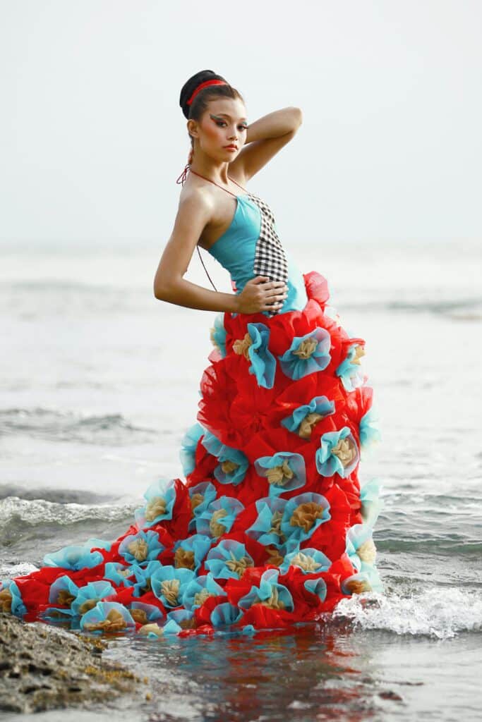 woman wearing high fashion red and turquoise dress in the ocean