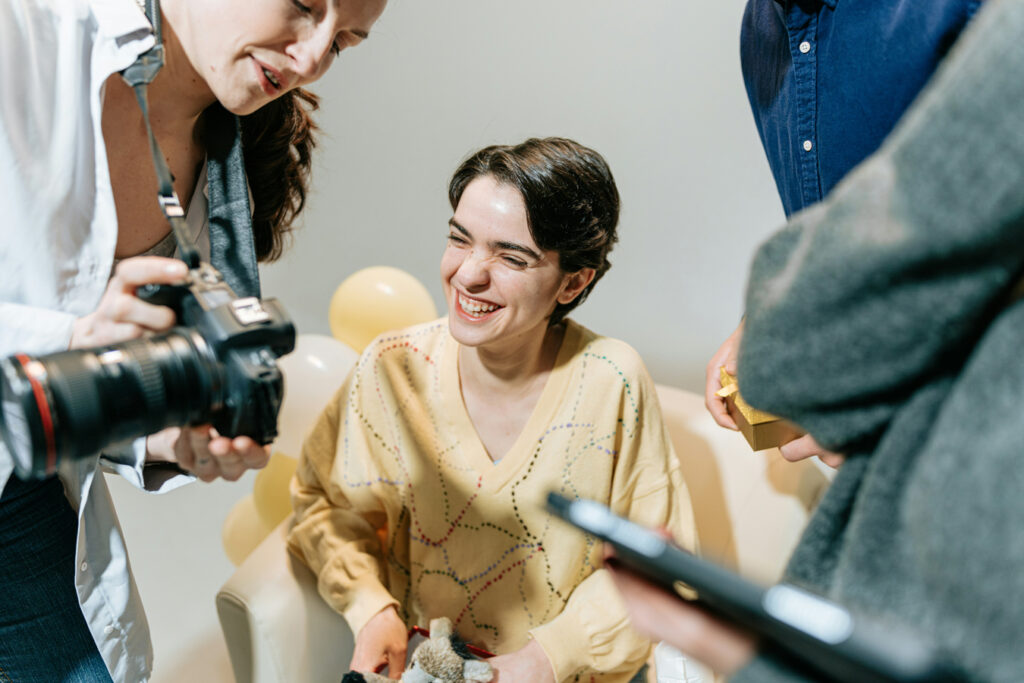 woman with short hair in yellow sweater laughing while photographer shows her the back of the camera