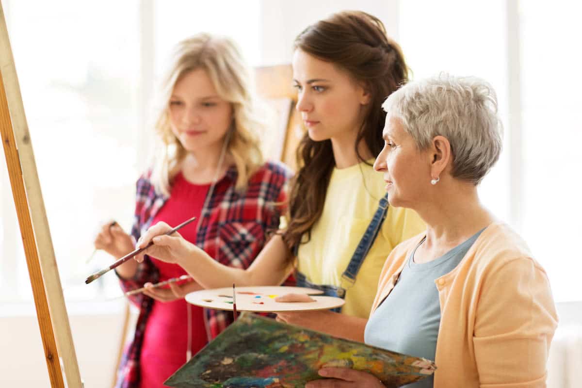 women-with-easel-and-palettes-at-art-school-PCUQEEC